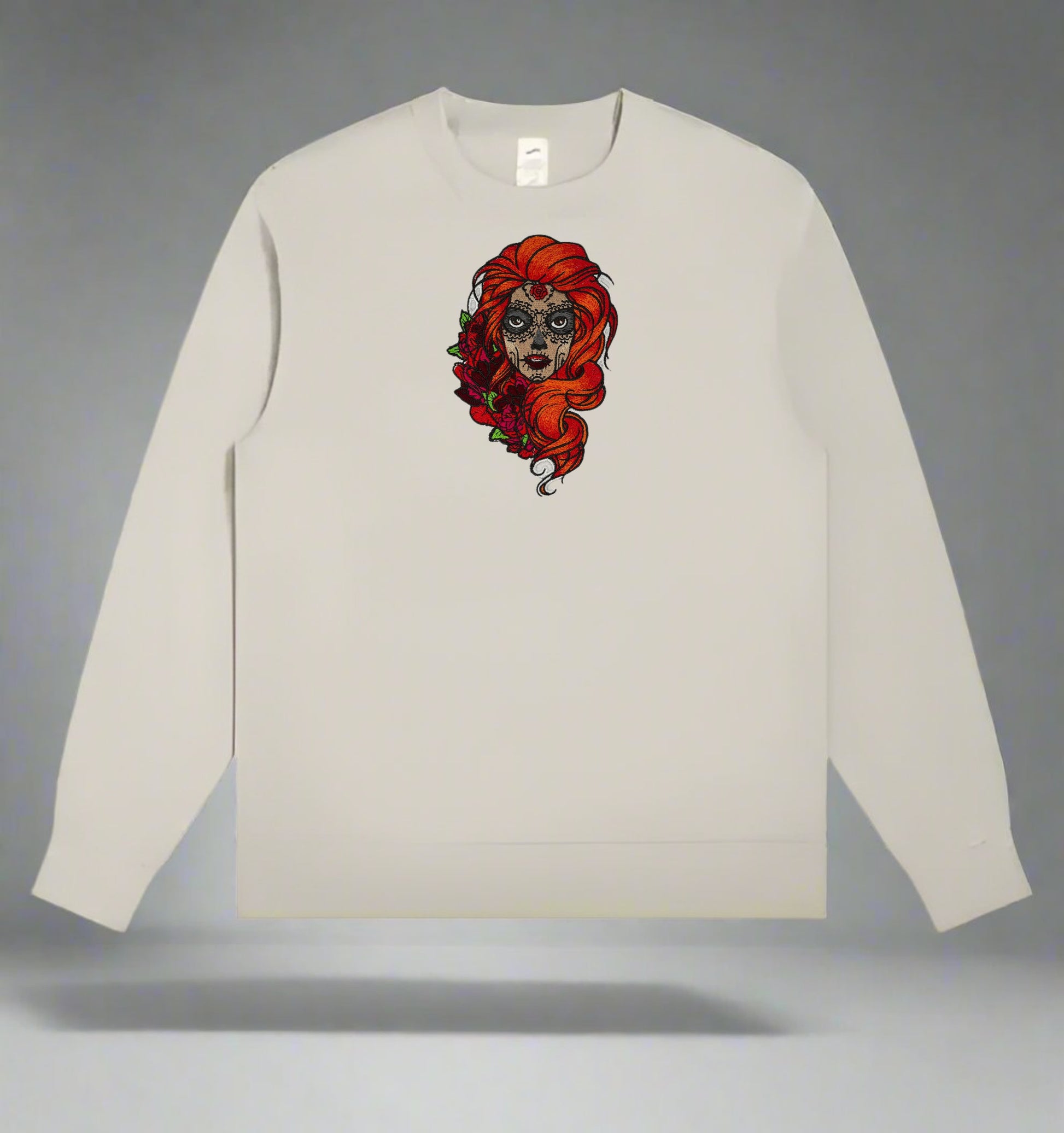 Beige long-sleeve shirt with a Sugar Skull Rose Embroidery – Artistic Heritage design of a woman with red hair on a gray background