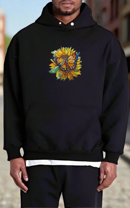 Embroidered hoodie featuring a colorful butterfly sitting on a sunflower with surrounding green leaves.