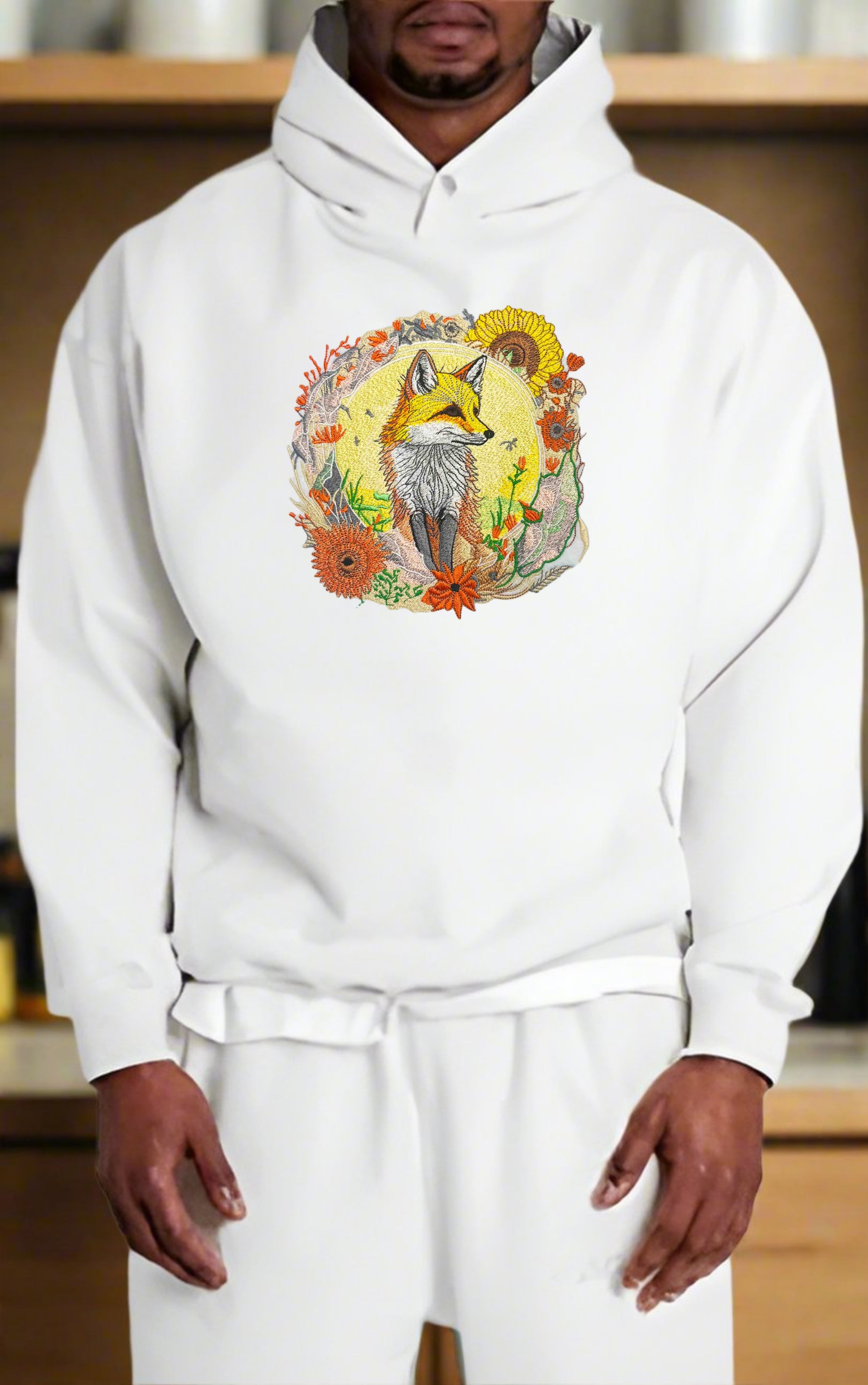 Embroidered hoodie featuring a golden fox surrounded by floral patterns, predominantly in shades of yellow, orange, and green.