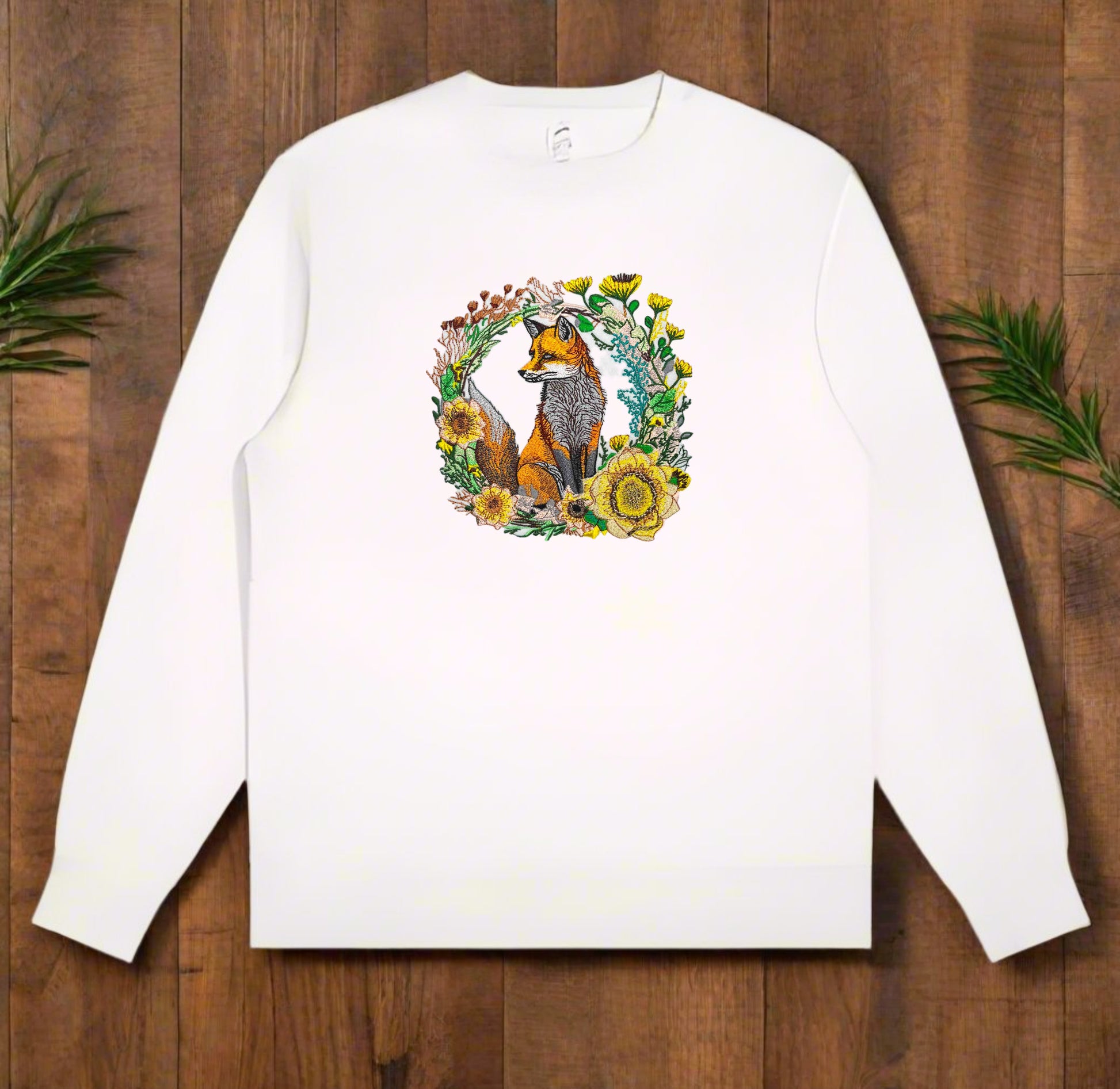 A detailed embroidered white sweatshirt  of a fox surrounded by floral patterns on a sweatshirt.