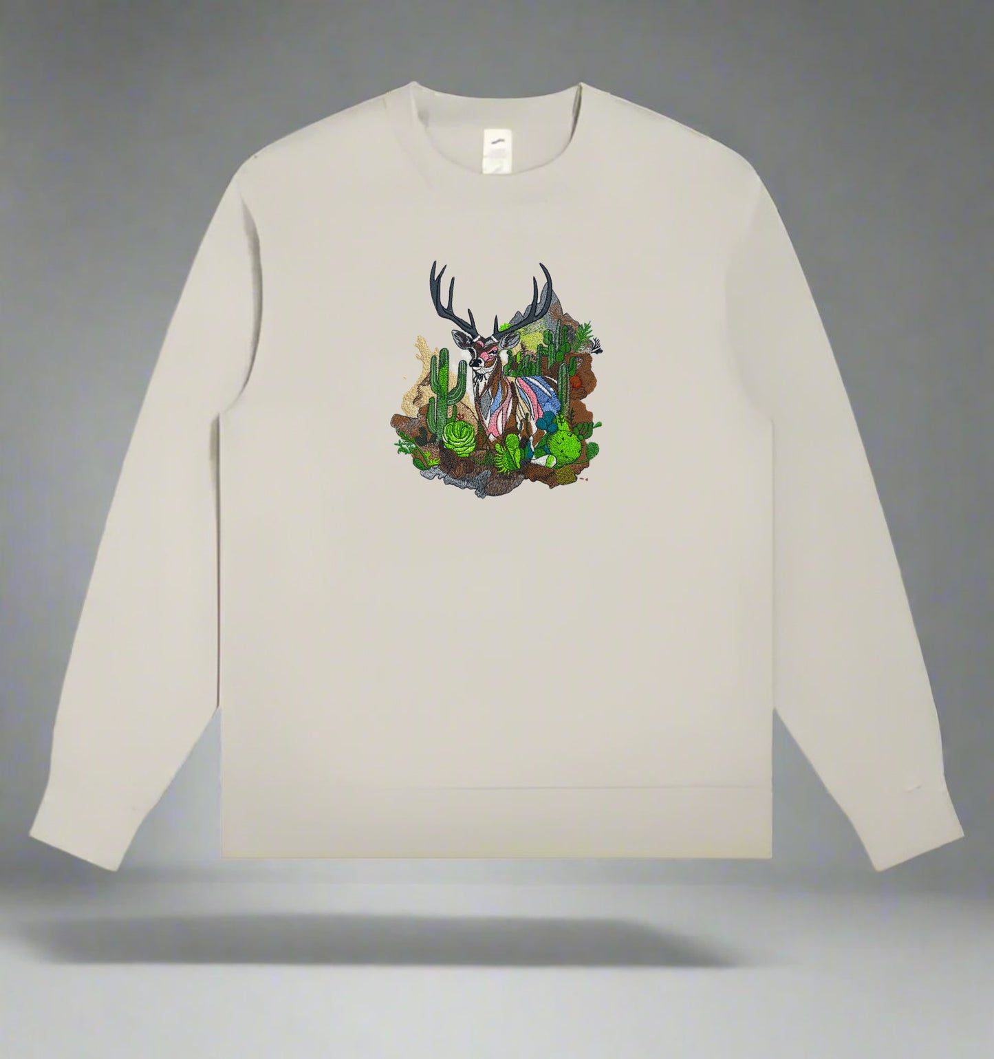 Embroidered crewneck sweatshirt with a design of a mountain deer among snow-dusted peaks and desert cacti.