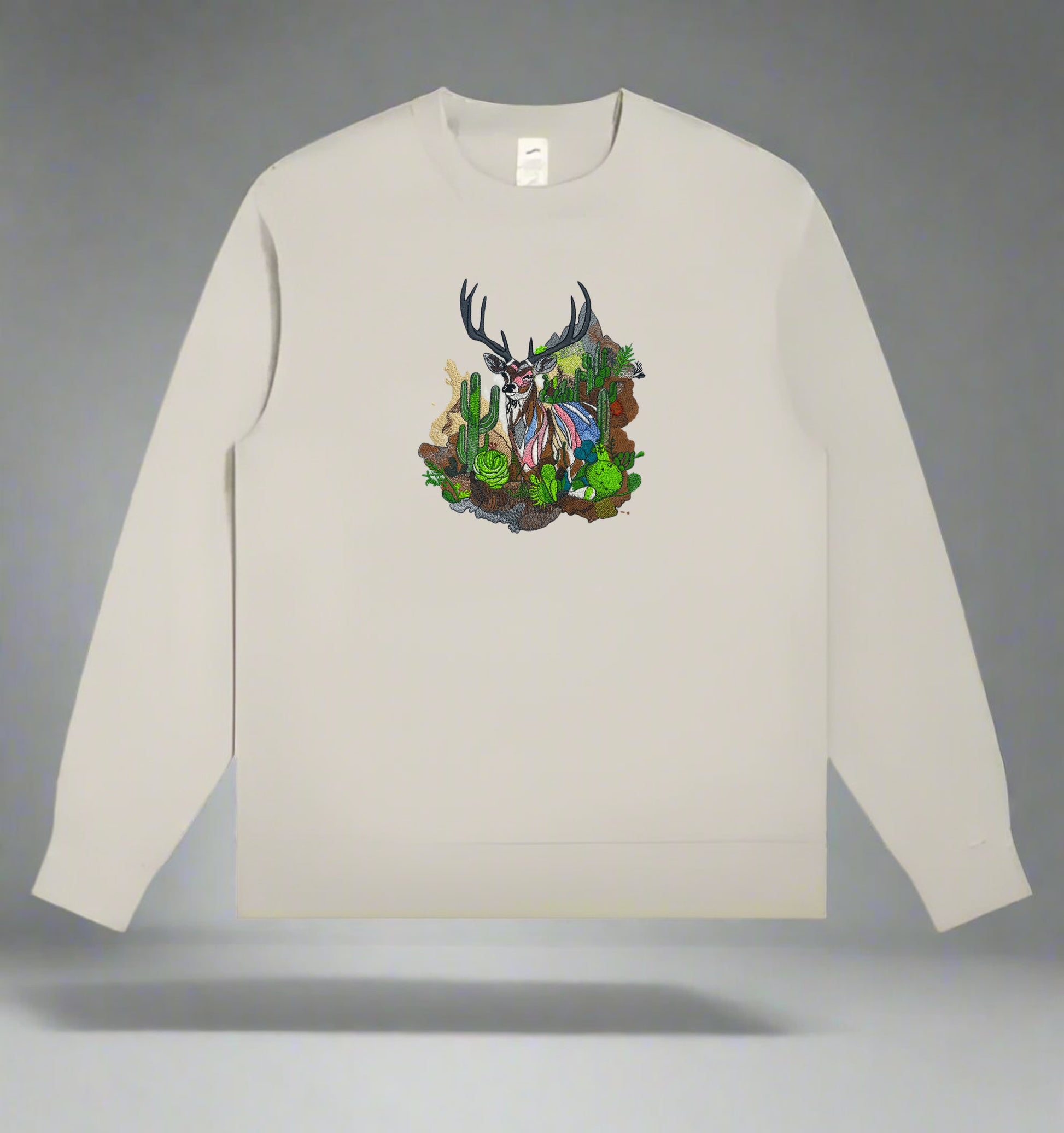 Embroidered crewneck sweatshirt with a design of a mountain deer among snow-dusted peaks and desert cacti.