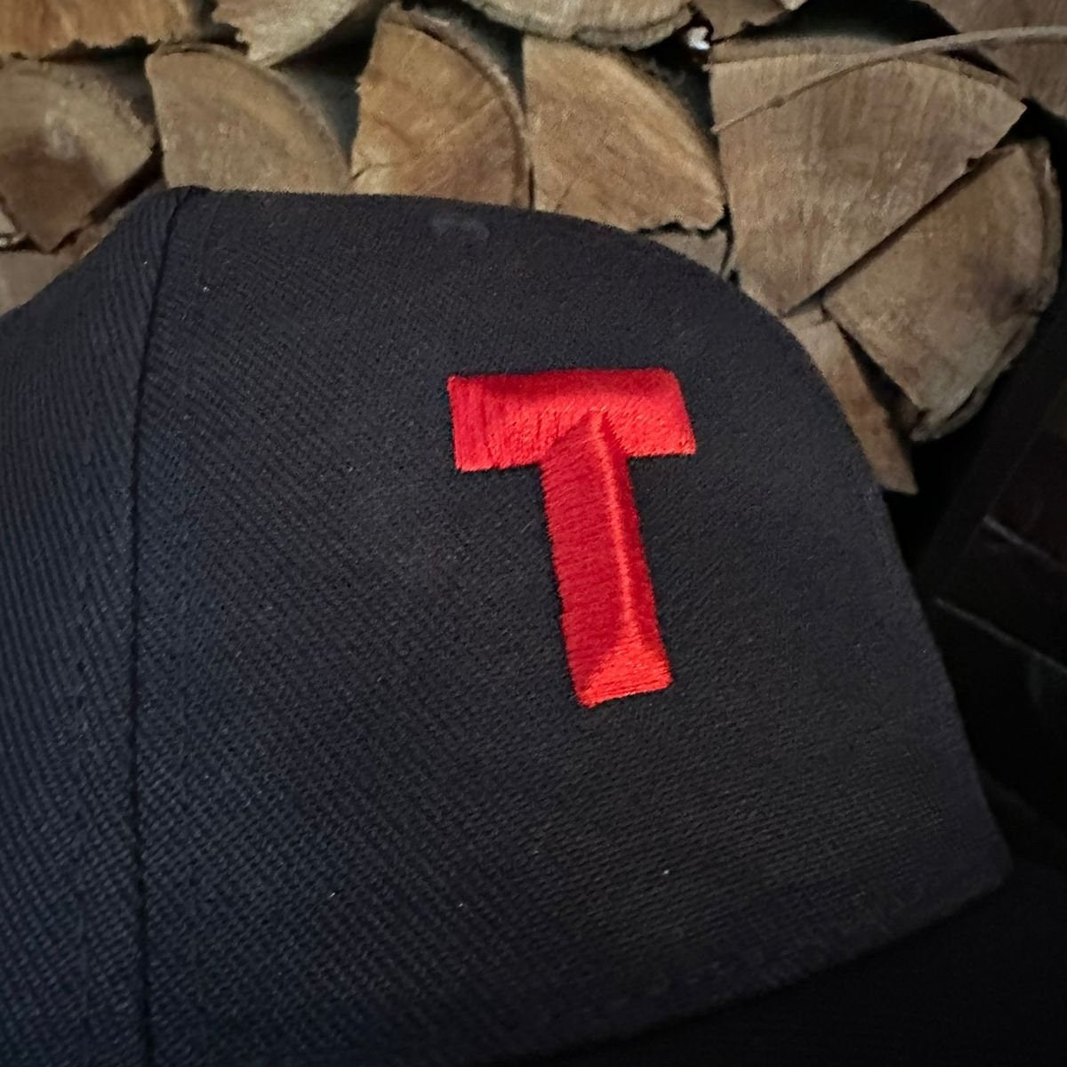 Black fabric with a red letter 'T' on a wooden background