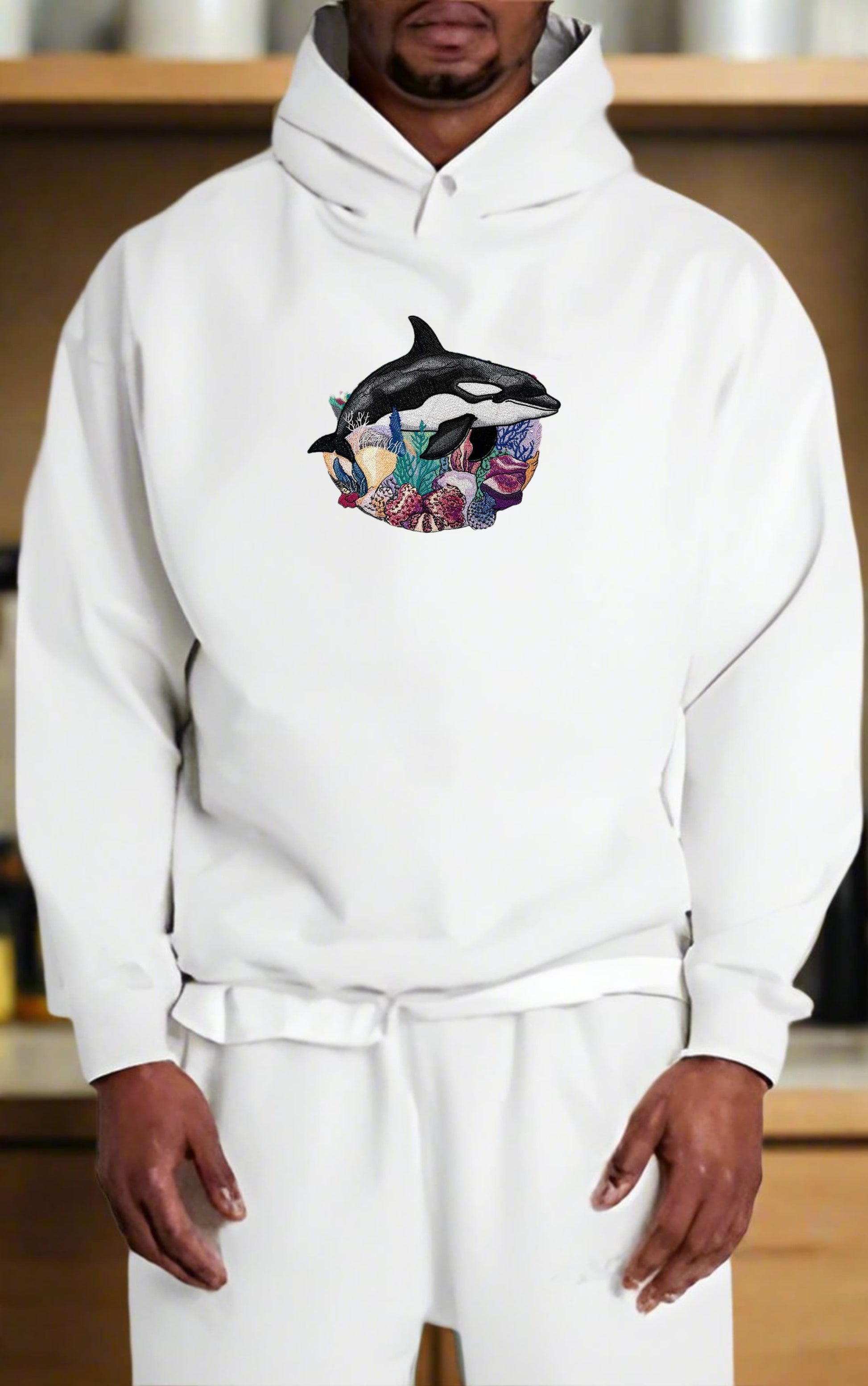 Person wearing a white hoodie with a colorful graphic design on a wooden shelf background