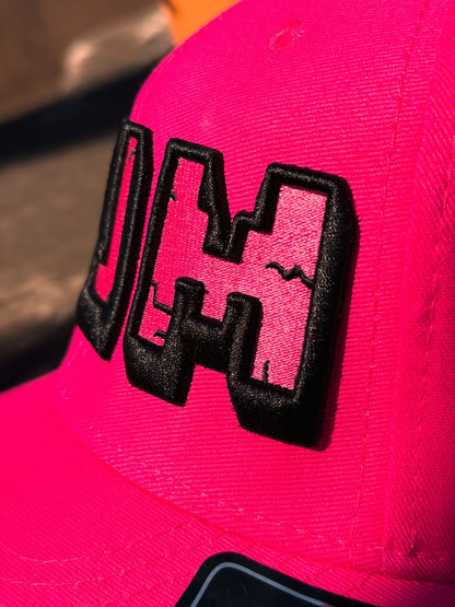 Close-up of a pink cap with a black logo on a blurred background