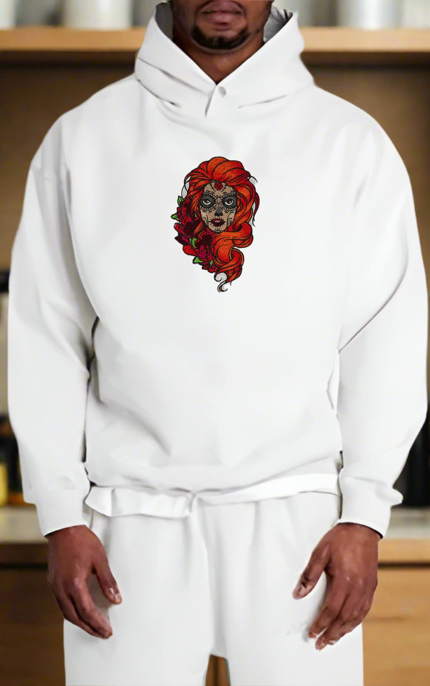 Person wearing a white hoodie with a  Sugar Skull Rose Girl Embroidery – Bold Artistic design on a neutral background