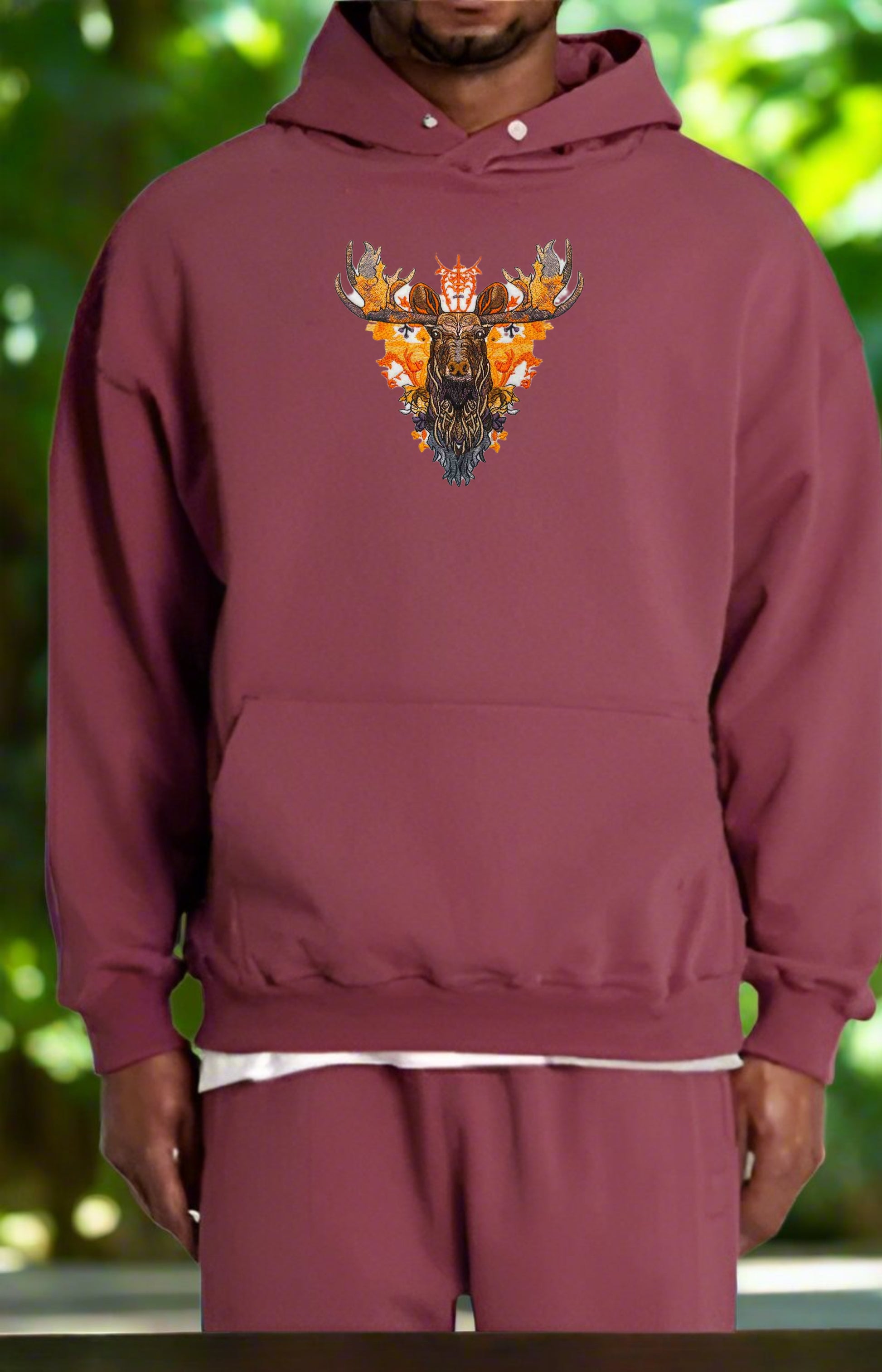Embroidered image of an orange moose with details of antlers and foliage in a fiery palette against a white background.
