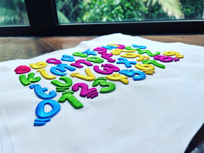 Colorful letters on a white fabric with a blurred green outdoor background