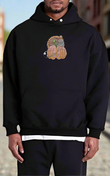 Person wearing a black hoodie with a  Pumpkin Bird & Sunflower Embroidery Design design on a blurred background