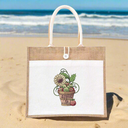 Jute bag with a floral design on a sandy beach with ocean in the background