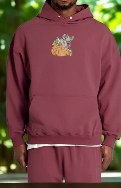 Maroon hoodie with a graphic design of a character on a pumpkin against a blurred green background