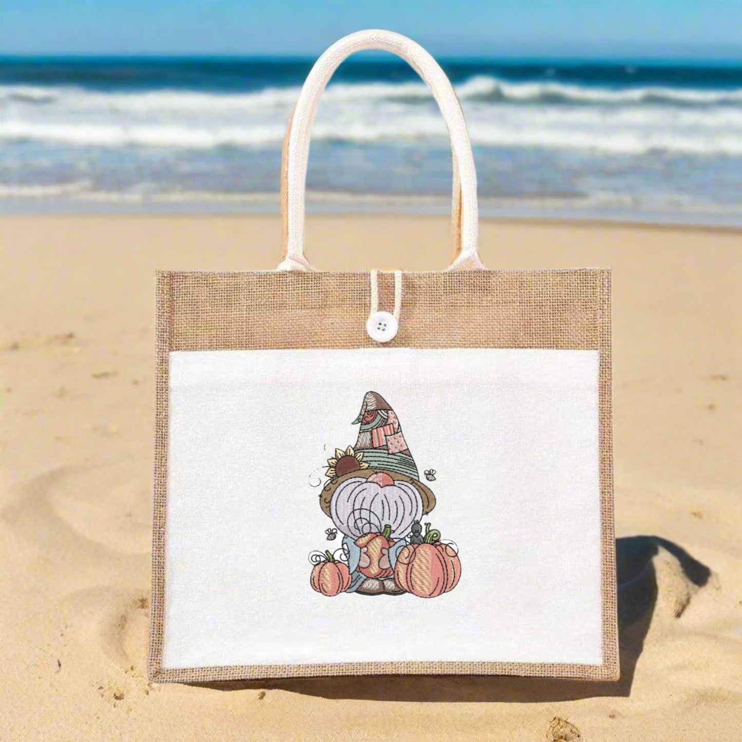 Jute bag with a cartoon gnome design on a sandy beach with ocean in the background