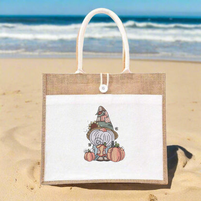 Jute bag with a cartoon gnome design on a sandy beach with ocean in the background