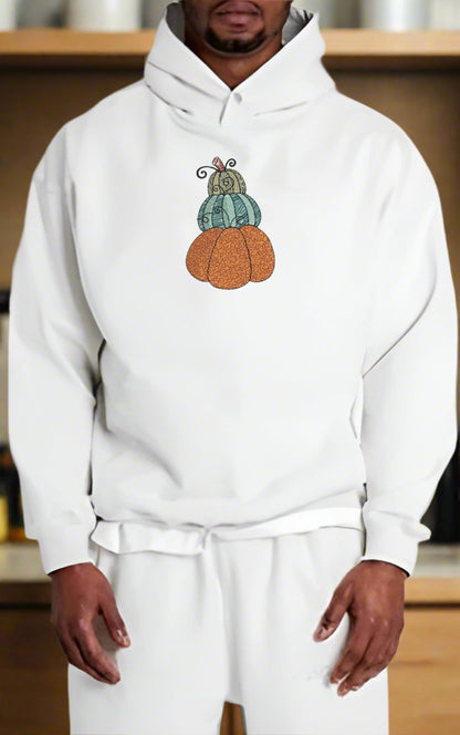 Person wearing a white hoodie with a pumpkin design on a neutral background