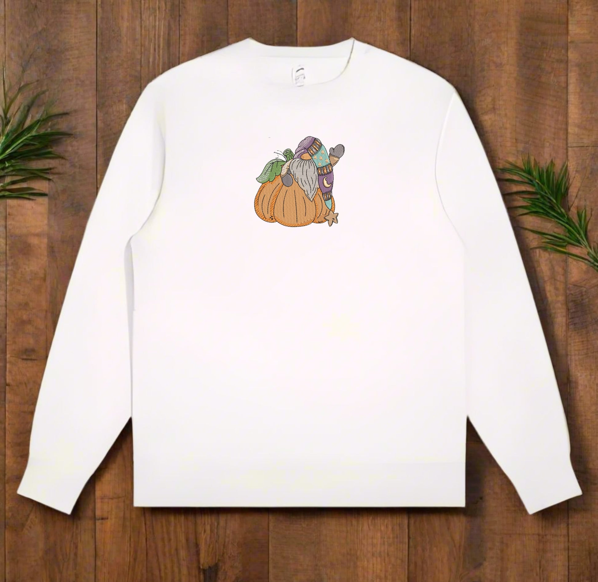 White long-sleeve sweatshirt with a graphic of a gnome on a pumpkin on a wooden surface.