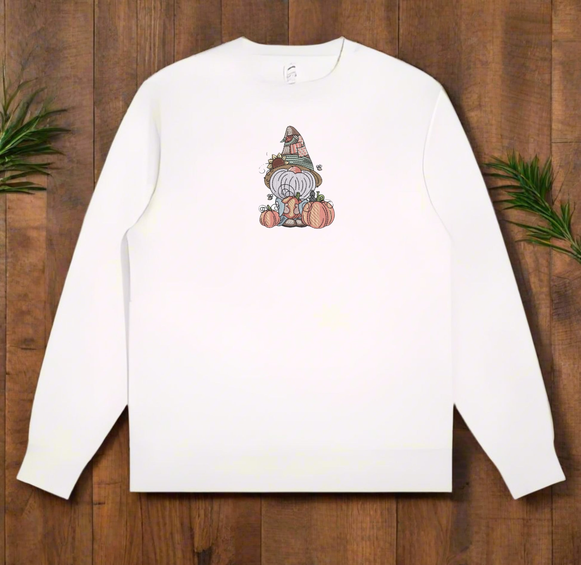 White long-sleeve sweatshirt with a gnome graphic on a wooden surface