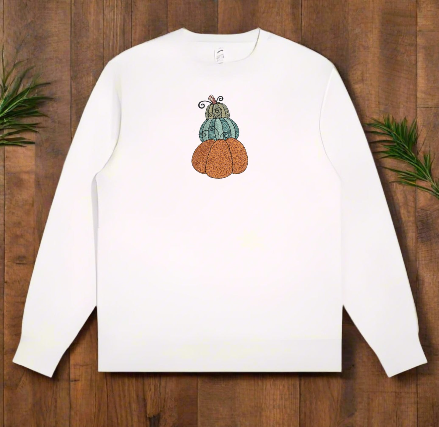 White long-sleeve sweatshirt with a pumpkin design on a wooden surface