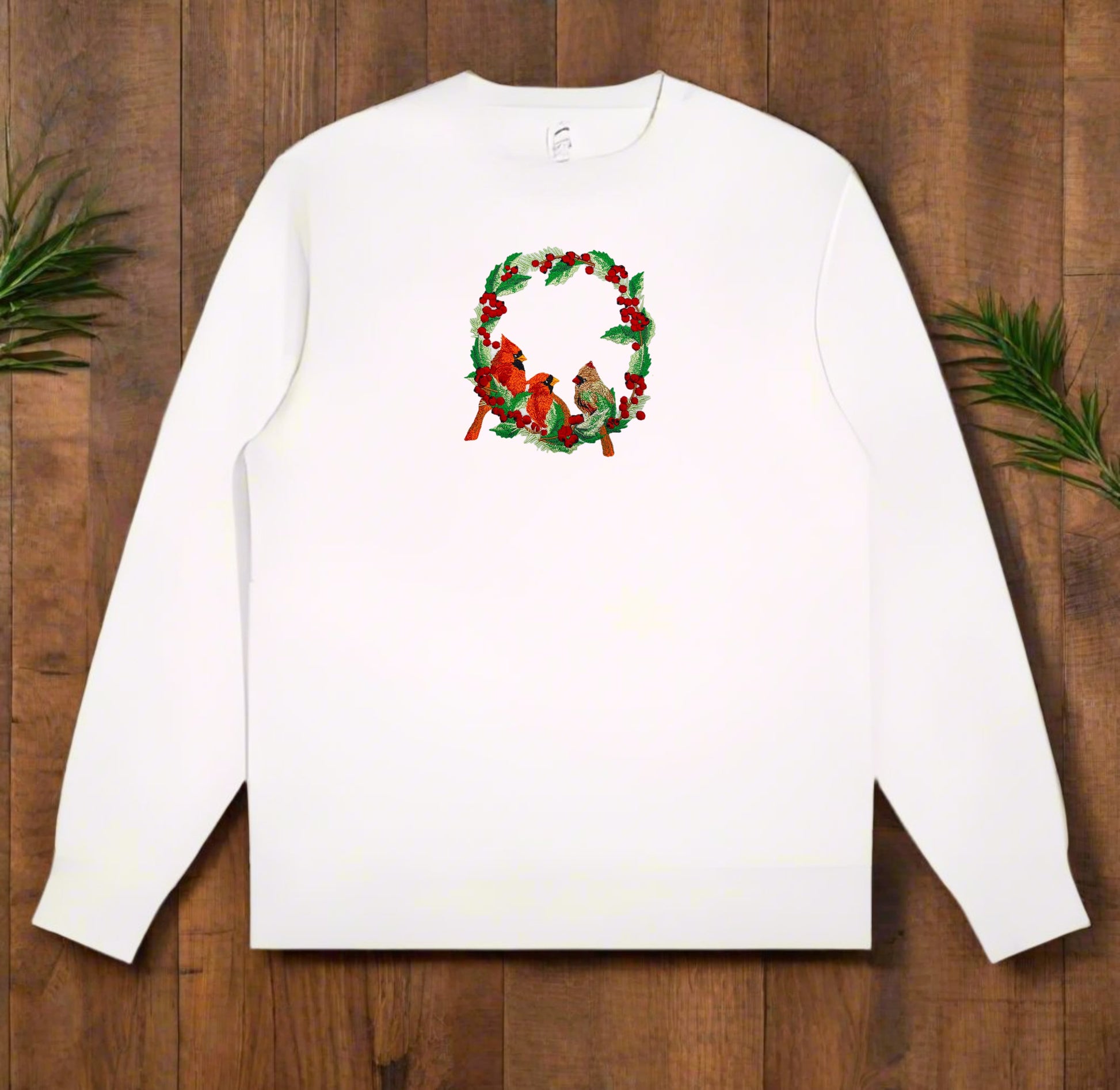Embroidered design featuring two red cardinals among green foliage with red berries on a white background.