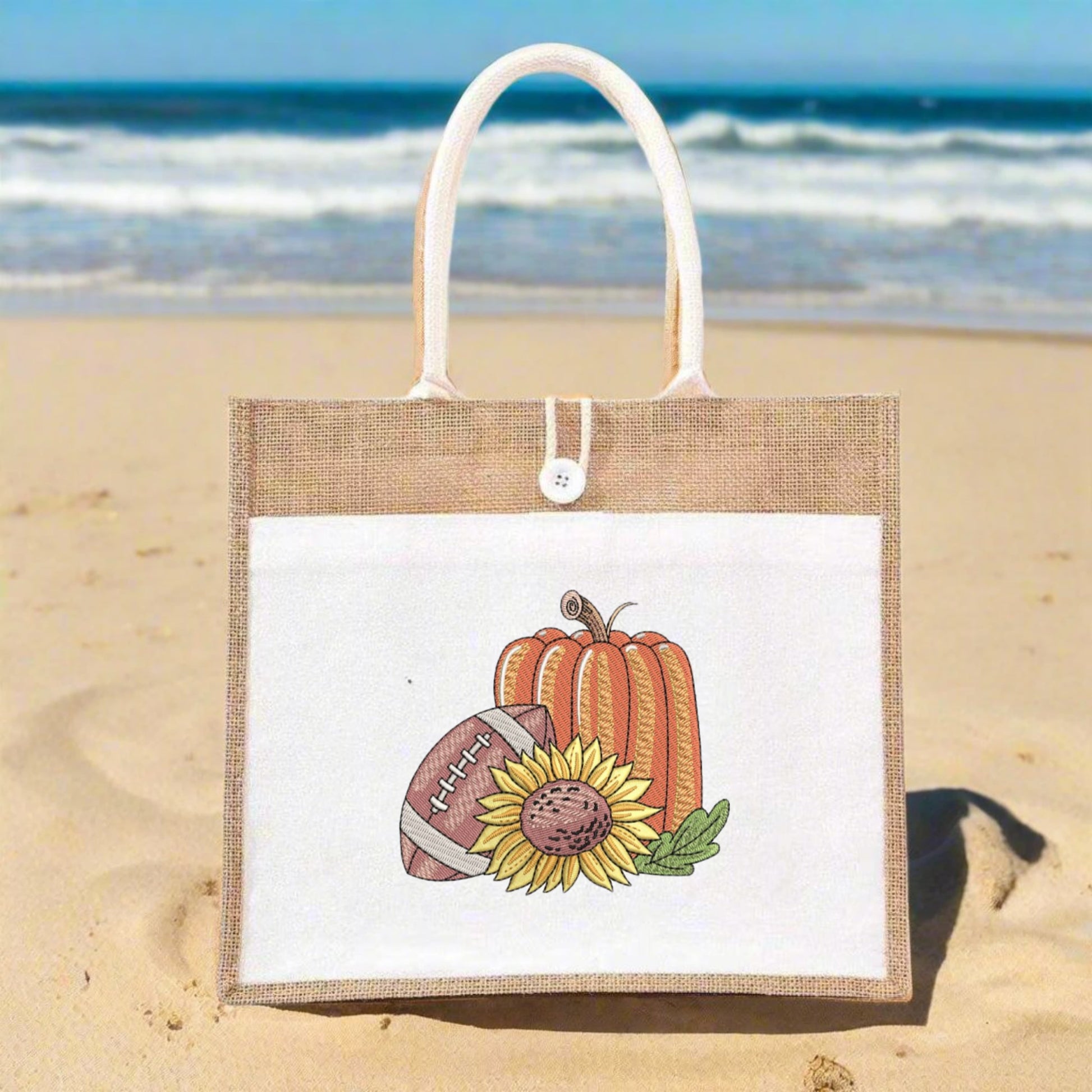 Jute bag with pumpkin, football, and sunflower design on a sandy beach.