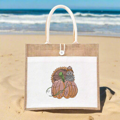 Jute bag with a pumpkin and owl design on a sandy beach with ocean in the background