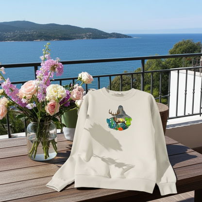 Mint green sweatshirt displayed on an outdoor balcony table with ocean view, featuring a desert deer landscape embroidery design, styled with a vase of pastel flowers in sunlight