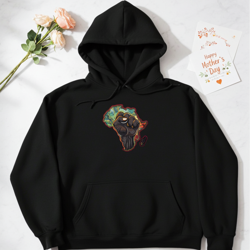 Black hoodie mockup featuring an embroidered raised fist over an Africa map design on the chest, styled flat lay with flowers and a Mother’s Day card.