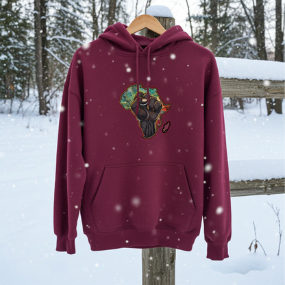 Burgundy hoodie mockup featuring an embroidered raised fist over an Africa map design on the chest, displayed outdoors in a snowy forest setting.