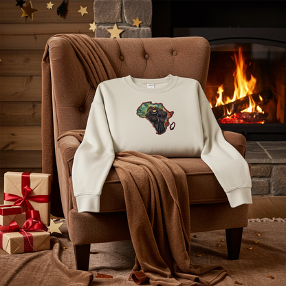 Mint green sweatshirt featuring an Africa map with a raised unity fist embroidery-style design, styled on an armchair by a cozy fireplace with wrapped gift boxes.