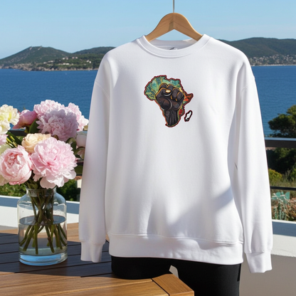 White sweatshirt featuring an Africa map with a raised unity fist embroidery-style design, displayed on a hanger on a balcony with ocean views and a vase of pink flowers.