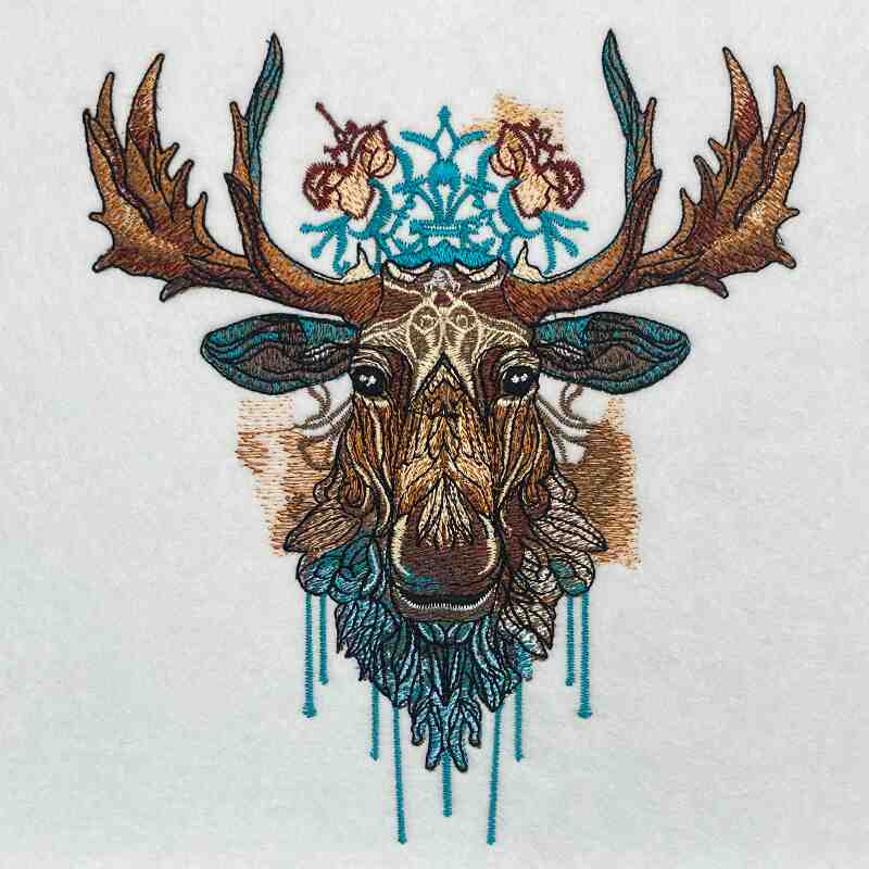 Close-up of an embroidered moose head with tribal-style details and turquoise accents, stitched on light fabric.
