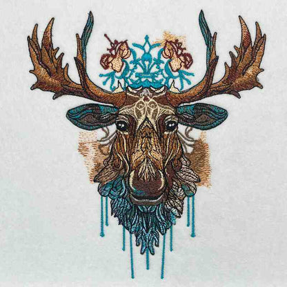 Close-up of an embroidered moose head with tribal-style details and turquoise accents, stitched on light fabric.