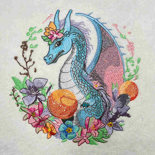 Close-up of an embroidered blue dragon surrounded by colorful flowers and leaves on a light fabric background.