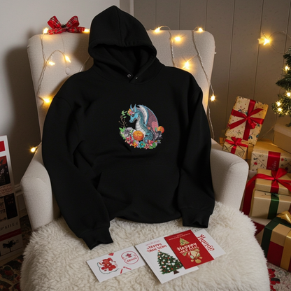 
Black hoodie mockup featuring an embroidered blue dragon surrounded by flowers on the chest, styled on an armchair with fairy lights, holiday cards, and wrapped gifts.