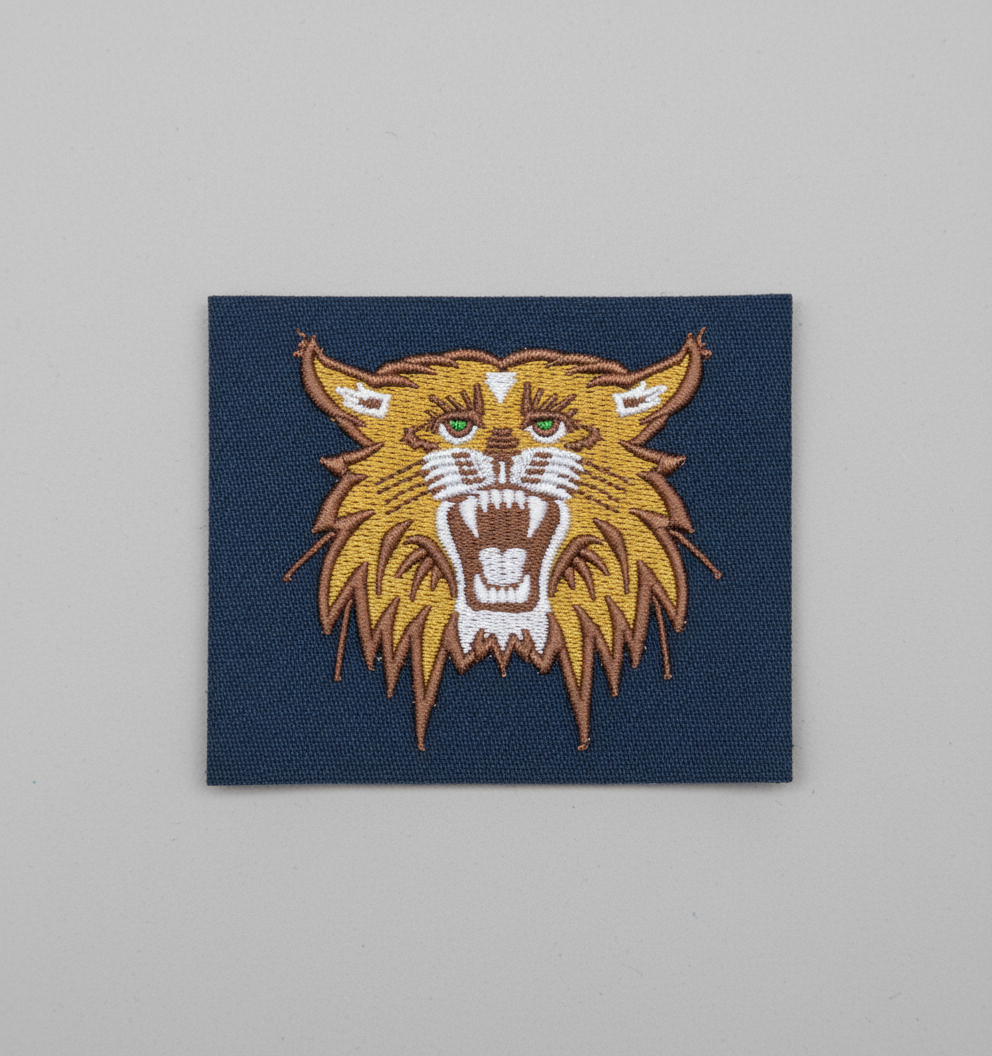 Embroidered design of a Bobcat head on a grid background