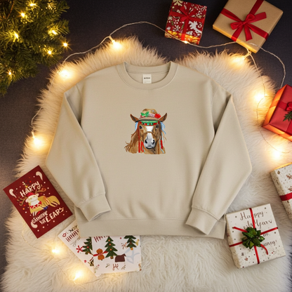 Mint green sweatshirt laid flat on a fluffy white rug with warm string lights, featuring colorful boho horse embroidery with a decorated hat, surrounded by wrapped gifts and holiday cards
