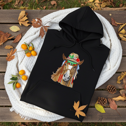 Black hoodie mockup featuring an embroidered boho western horse wearing a decorated hat on the chest, styled with autumn leaves, pinecones, and a cozy white knit blanket.