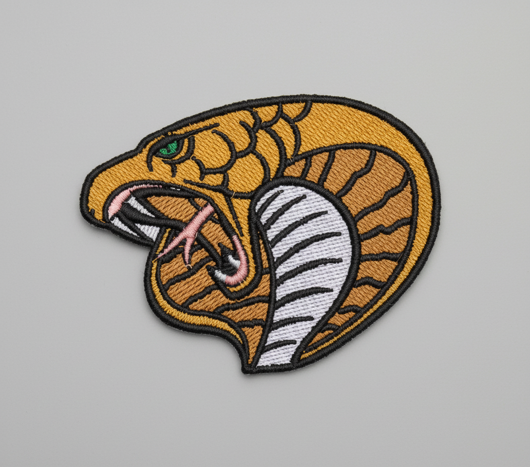 Embroidered patch of a snake's head on a grid background