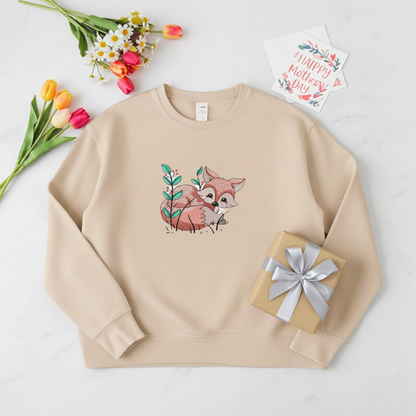 Beige sweatshirt featuring a cute woodland fox embroidery-style design, styled flat lay with tulips, a wrapped gift, and a Mother’s Day card.