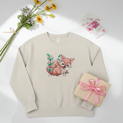 Mint green sweatshirt featuring a cute woodland fox embroidery-style design, styled flat lay with a bouquet of flowers, a wrapped gift with pink ribbon, and a Mother’s Day card.