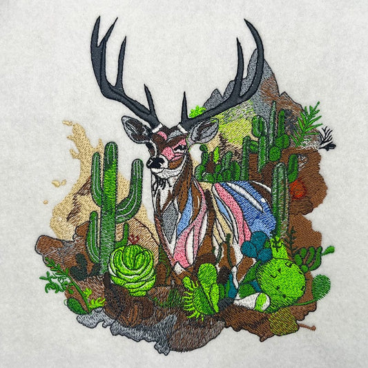 Embroidered crewneck sweatshirt with a design of a mountain deer among snow-dusted peaks and desert cacti.