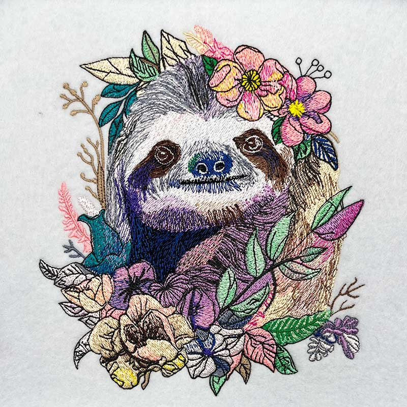 Embroidered design of a sloth surrounded by flowers and leaves on a white background