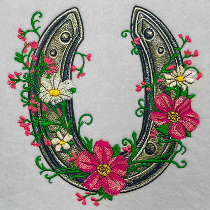 Embroidered design of a horseshoe with floral elements on a gray background