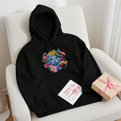 Black hoodie mockup featuring an embroidered blue cat face surrounded by colorful flowers on the chest, styled on an armchair with a gift box and a Mother’s Day card.
