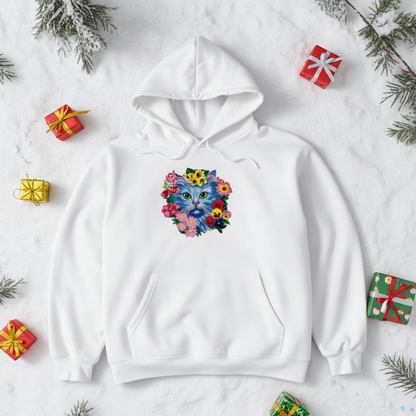 
White hoodie mockup featuring an embroidered blue cat face surrounded by colorful flowers on the chest, styled on a snowy background with small wrapped gifts and evergreen branches.