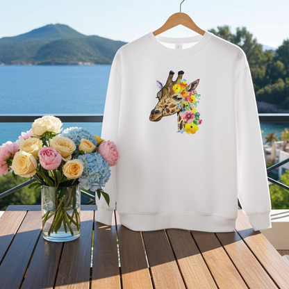 White sweatshirt hanging on a balcony with ocean view, featuring a giraffe head embroidery with colorful floral accents, styled with a vase of fresh flowers on a wooden table