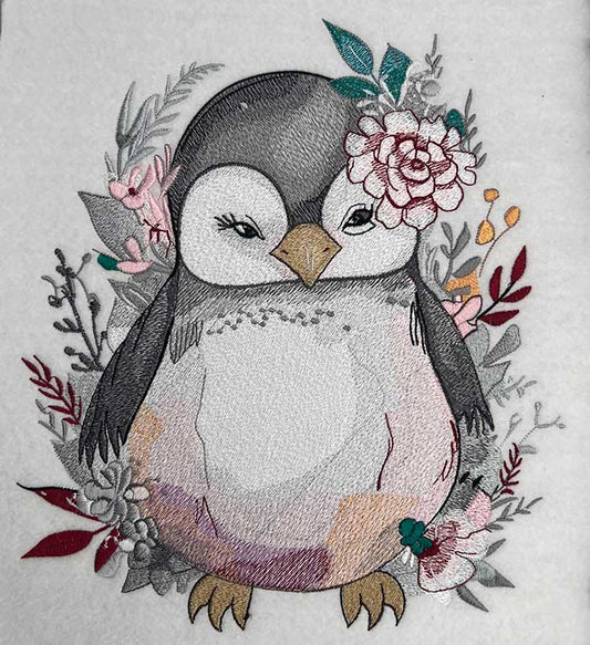A design  featuring embroidered penguin and floral designs on a beige fabric.