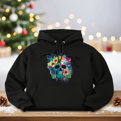 Black hoodie mockup featuring an embroidered colorful floral skull on the chest, photographed on a wooden surface with snow and pinecones, with a blurred Christmas tree and warm string lights in the background.