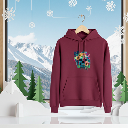 Burgundy hoodie mockup featuring an embroidered colorful floral skull on the chest, displayed on a hanger in a winter-themed scene with snowy mountain view, paper pine trees, and hanging snowflake decorations.