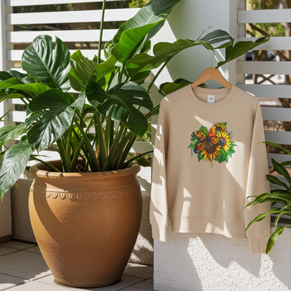 Soft beige sweatshirt hanging outdoors on a white balcony railing, featuring colorful butterfly and sunflower embroidery on the chest, surrounded by lush green plants in terracotta pots