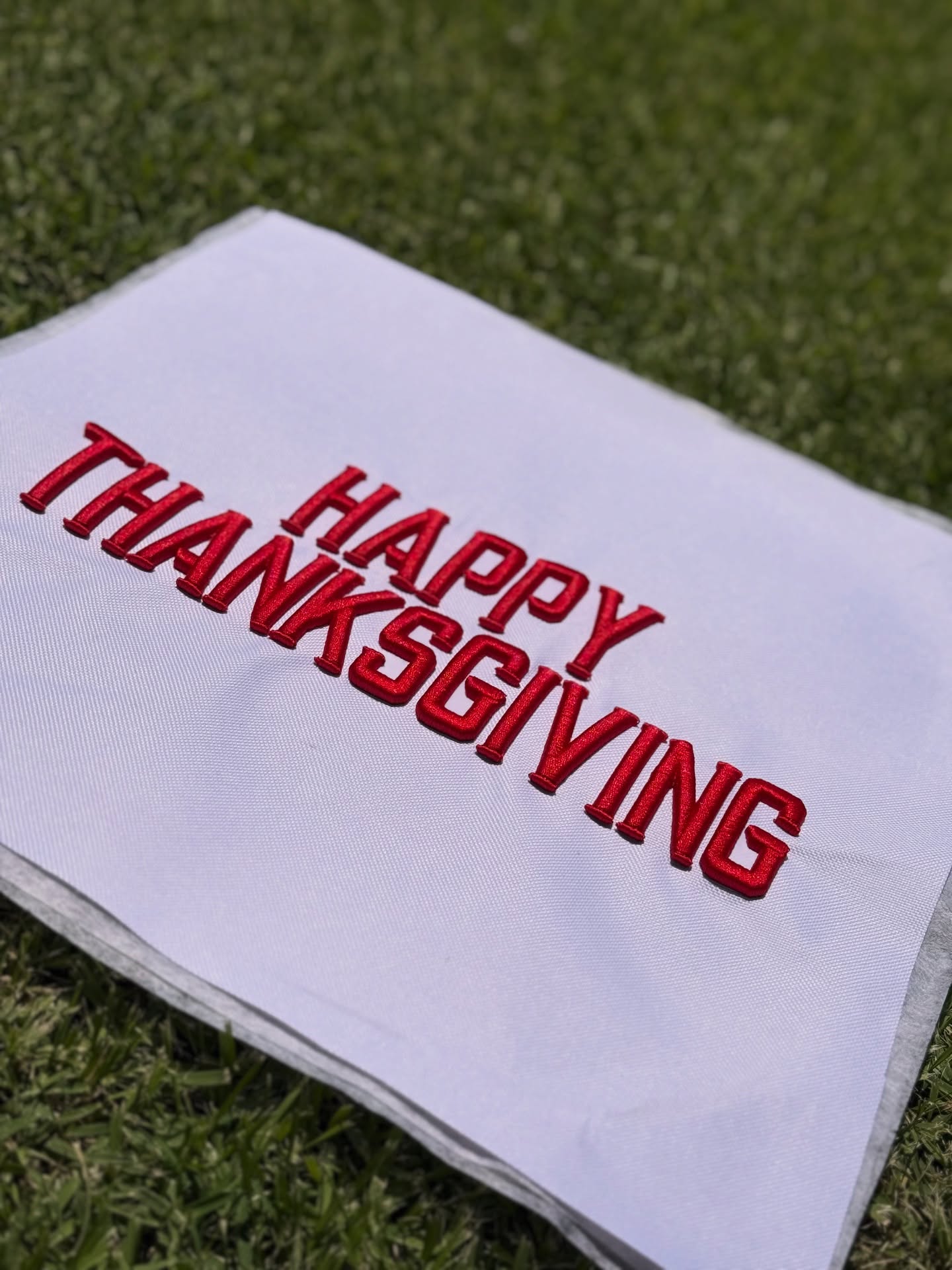 White towel with 'Happy Thanksgiving' in red on a grass background